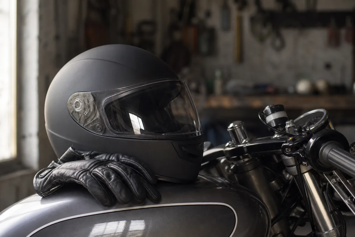 Casque et gants de moto posés sur le réservoir avant un cours